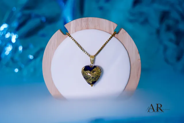 Ciondolo a cuore in vetro blu e oro su espositore in legno, sfondo azzurro